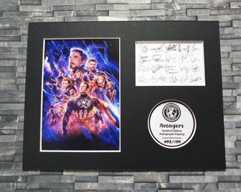 May include: A framed print of the Avengers movie poster with a black background. The poster features the Avengers characters in a dramatic pose. The frame includes a white mat and a black and white circular sticker with the text "Avengers Limited Edition Autograph Display 002/100".