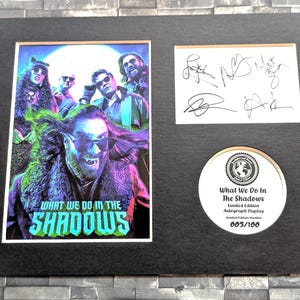 Pu&ograve; includere: Un poster incorniciato e firmato del cast dello show televisivo "What We Do in the Shadows". Il poster presenta un'immagine colorata dei membri del cast, con il titolo dello show in un font stilizzato. Il poster &egrave; numerato 003/100, a indicare che fa parte di un'edizione limitata.