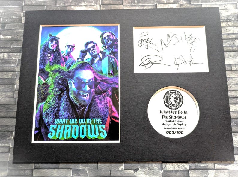 Pu&ograve; includere: Un poster incorniciato e firmato del cast dello show televisivo "What We Do in the Shadows". Il poster presenta un'immagine colorata dei membri del cast, con il titolo dello show in un font stilizzato. Il poster &egrave; numerato 003/100, a indicare che fa parte di un'edizione limitata.