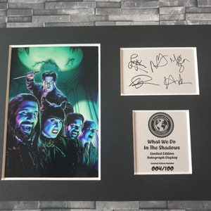 Pu&ograve; includere: Un'esposizione autografata in edizione limitata incorniciata del cast dello show televisivo "What We Do in the Shadows". L'esposizione presenta una foto in bianco e nero del cast su uno sfondo verde. L'esposizione &egrave; numerata 004/100.