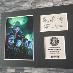 Pu&ograve; includere: Un'esposizione autografata in edizione limitata incorniciata del cast dello show televisivo "What We Do in the Shadows". L'esposizione presenta una foto in bianco e nero del cast con un bagliore verde e viola. Le firme sono in inchiostro nero su sfondo bianco. L'esposizione &egrave; numerata 004/100.