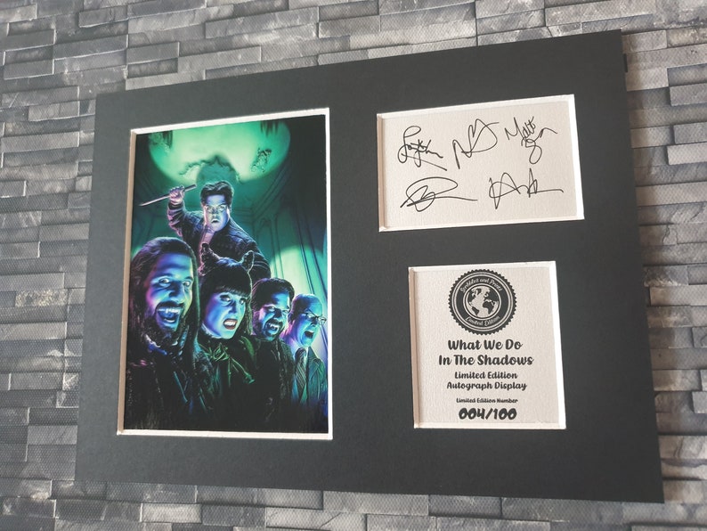 Pu&ograve; includere: Un'esposizione autografata in edizione limitata incorniciata del cast dello show televisivo "What We Do in the Shadows". L'esposizione presenta una foto in bianco e nero del cast con un bagliore verde e viola. Le firme sono in inchiostro nero su sfondo bianco. L'esposizione &egrave; numerata 004/100.