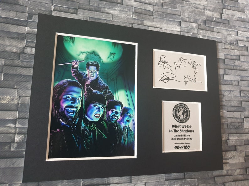Pu&ograve; includere: Una stampa incorniciata del cast dello show televisivo "What We Do in the Shadows" con le loro autografi. La stampa &egrave; un'illustrazione colorata dei personaggi in un'ambientazione spettrale. La cornice &egrave; nera con un passepartout bianco. La stampa &egrave; numerata 004/100.
