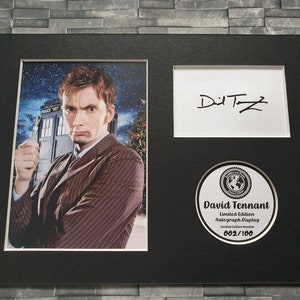 May include: A black framed photograph of David Tennant, the tenth Doctor Who, holding a sonic screwdriver. The photo is signed "David Tennant" and includes a limited edition autograph display with the number 002/100.