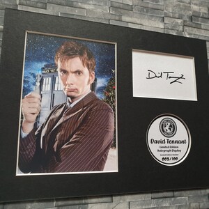 May include: A black framed photograph of David Tennant, the tenth Doctor Who, holding a sonic screwdriver. The photo is signed "David Tennant" and includes a limited edition autograph display numbered 002/100.