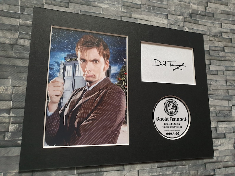 May include: A black framed photograph of David Tennant, the tenth Doctor Who, holding a sonic screwdriver. The photo is signed "David Tennant" and includes a limited edition autograph display numbered 002/100.