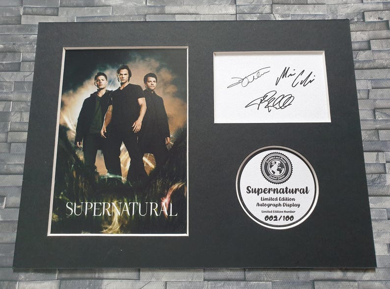 May include: A black framed print of a photo of three men from the TV show Supernatural. The print is signed by the actors and includes a Supernatural Limited Edition Autograph Display label with the number 002/100.