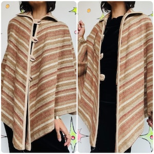 Puede incluir: Un poncho vintage en tonos marrón, beige y crema con rayas horizontales. El poncho presenta un cuello, tres cierres de palanca de madera y un ribete beige. La prenda está hecha de una tela tejida y tiene un corte holgado.