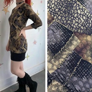 May include: A long-sleeved mini dress with a brown and black snakeskin pattern on the top and a black skirt. The dress has a round neckline and three-quarter sleeves. The fabric swatch shows a close-up of the snakeskin pattern.