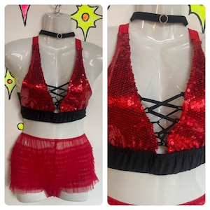 May include: Red sequined lingerie set with black trim and lace-up detail. The set includes a bra and a ruffled skirt.