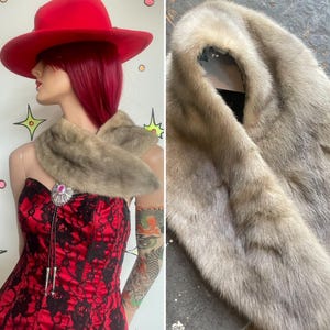 Könnte beinhalten: Eine beige Pelzstola mit weicher, dichter Textur und zulaufender Form. Die Stola weist einen hellbraunen und grauen Farbverlauf über die gesamten Fellfasern auf und bietet einen neutralen Ton, der einen Kontrast zur roten und schwarzen Kleidung bildet.