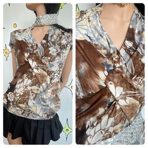 May include: A short-sleeved top with a V-neckline, featuring a floral pattern in shades of brown, beige, and gray. The top has a wrap-style design and is paired with a black skirt. A sequined collar adds a touch of sparkle.