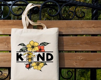 May include: Beige tote bag with a floral and bee design. The word "KIND" is printed in black, with a bee graphic in the center. Yellow and orange flowers and green leaves surround the bee. The bag has long handles.