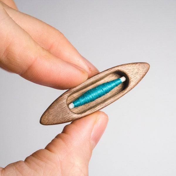 Shuttlie (mini shuttle) made of black walnut wood with teal cotton bobbin by Polleda