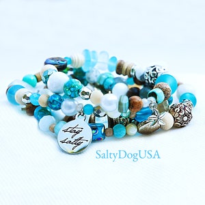 May include: A set of five bracelets featuring a mix of blue, white, and brown beads. The bracelets have a charm that says "Stay Salty".