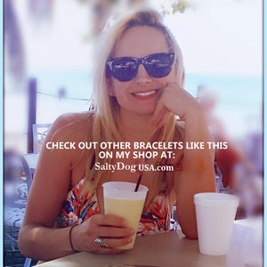 Op de afbeelding: Een vrouw met een zonnebril en een kleurrijk topje houdt een glas met een gele drank. De tekst op de afbeelding luidt "Check out other bracelets like this on my shop at: SaltyDogUSA.com".