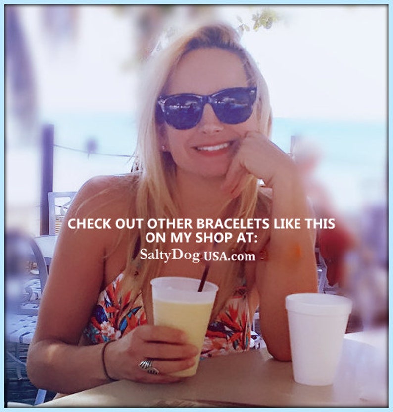 Op de afbeelding: Een vrouw met een zonnebril en een kleurrijk topje houdt een glas met een gele drank. De tekst op de afbeelding luidt "Check out other bracelets like this on my shop at: SaltyDogUSA.com".