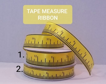 May include: Yellow tape measure ribbon with black markings. The ribbon is wound around a spool and shows the numbers 1, 2, 3, 4, 5, 6, 7, 8, 9, 10, 11, and 12.