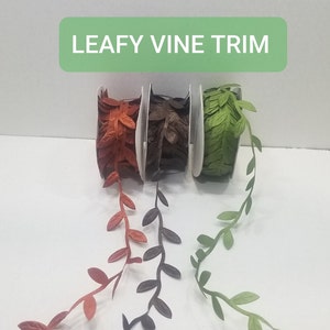 May include: Three spools of leafy vine trim. The trim is in three colors: green, brown, and orange. The trim is made of fabric and has a leafy design. The trim is labeled "Leafy Vine Trim".