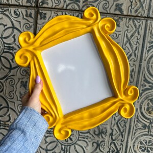 Pu&ograve; includere: Una cornice per foto in plastica gialla con un design ondulato e decorato. La cornice &egrave; vuota e pronta per una foto.