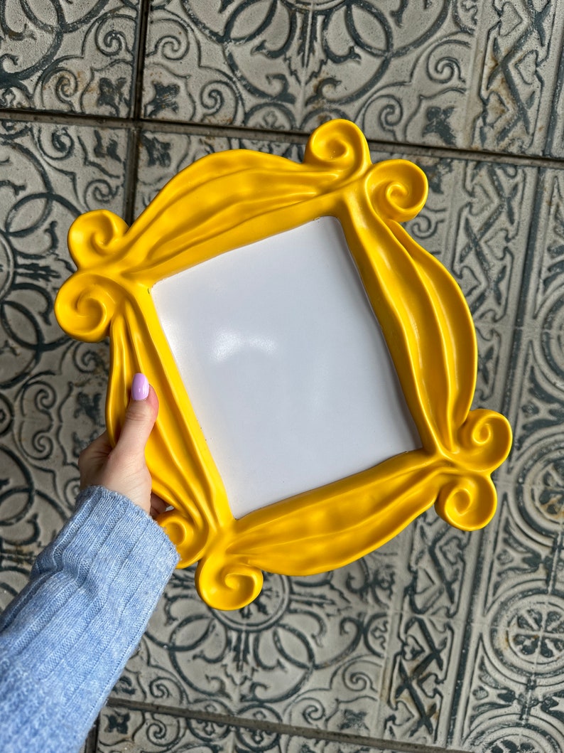 Pu&ograve; includere: Una cornice per foto in plastica gialla con un design ondulato e decorato. La cornice &egrave; vuota e pronta per una foto.