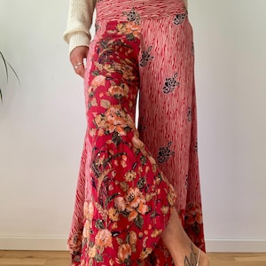 Puede incluir: Pantalones de pierna ancha con una base de color rojo vibrante que combina estampados florales y rayas tipo cebra. La prenda cuenta con una cintura alta elástica y una silueta holgada y fluida que llega hasta el suelo, mostrando detalles botánicos.