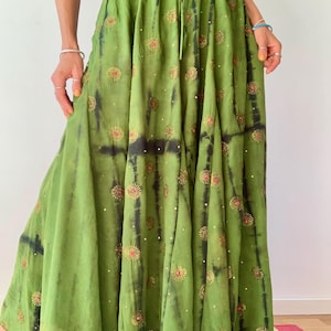 Könnte beinhalten: Ein fließender, limettengrüner Rock mit Bindeband. Der Rock hat einen Batik-Effekt mit dunkelgrünen Akzenten und ist mit gestickten Blumenmustern in Gold und Rot verziert. Der Rock ist aus leichtem Stoff gefertigt, ideal für warmes Wetter. Ca. 90 cm lang.