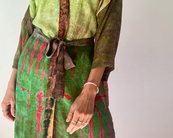 May include: A green, red, and brown silk robe with a tie belt. The robe has a tie closure and a V-neck.