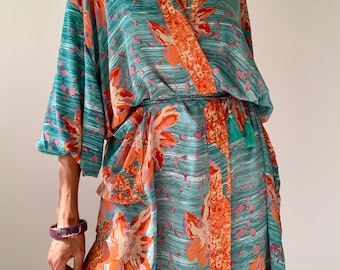 May include: A teal blue and orange floral print kimono robe with a long, flowing silhouette and a sash tie. The robe has a tassel detail on the sash.