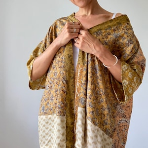 May include: A gold and cream patterned kimono with a patchwork design. The kimono has a long, flowing silhouette and is made of a soft, silky fabric.