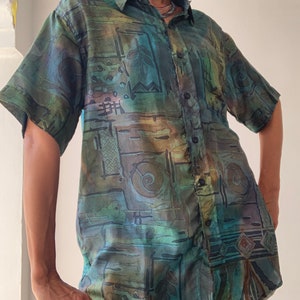May include: A short-sleeved button-down shirt with an abstract geometric pattern in shades of green, blue, and brown.