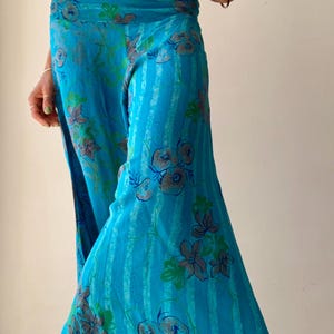 May include: Flowing, wide-leg pants in a vibrant turquoise hue, adorned with a floral pattern in shades of gray and green. The pants feature vertical stripes and a comfortable, relaxed fit, perfect for warm weather.