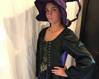 May include: A purple and black witch costume with a long black satin skirt, a purple and black bodice with gold accents, and a tall purple witch hat with a black brim.