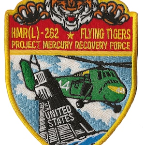 May include: A yellow, red, and blue embroidered patch with a tiger, a helicopter, and the text "HMR(L)-262 * FLYING TIGERS PROJECT MERCURY RECOVERY FORCE".