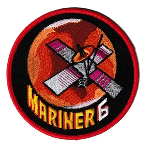 May include: Embroidered patch depicting the Mariner 6 spacecraft against an orange and red planet. The patch has a black border with the text "MARINER 6" in yellow and white.