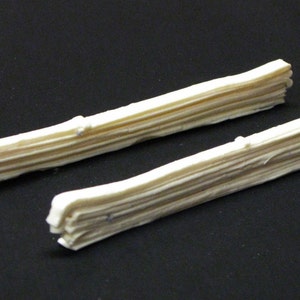 Puede incluir: Dos piezas decorativas de madera blanca, cada una con un diseño en capas y apilado. Las piezas son de tamaño y forma similares y están dispuestas una al lado de la otra.