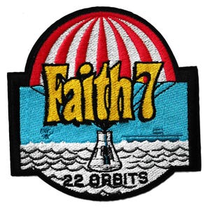 May include: Embroidered patch with the words "Faith 7" in yellow, above a blue background with a submarine and a science beaker. The patch has a red and white striped parachute design at the top and the words "22 ORBITS" at the bottom.