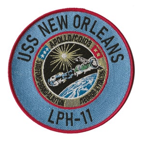 May include: A blue and red embroidered patch with the text "USS NEW ORLEANS LPH-11" and a depiction of a spacecraft in orbit around Earth.