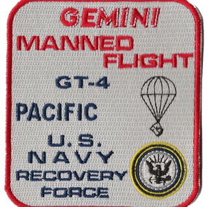May include: A white patch with red trim, featuring the text "GEMINI MANNED FLIGHT GT-4 PACIFIC U.S. NAVY RECOVERY FORCE" in blue and red. A parachute and a navy seal emblem are also featured.