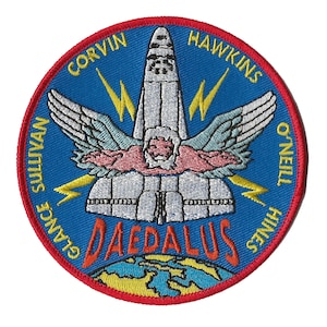 May include: A blue and white embroidered patch with a space shuttle, wings, and lightning bolts. The text "DAEDALUS" is in the center of the patch. The names "GLANCE SULLIVAN", "CORVIN HAWKINS", and "THINES O'NEILL" are around the edge of the patch.