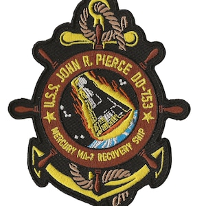 Op de afbeelding: Een geborduurde patch in zwart en geel met een scheepswiel en een anker. De tekst luidt "USS John R. Pierce DE 753* Mercury MA-7 Recovery Ship".