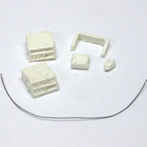 May include: A set of white plastic model parts for a truck, including a cab, a bed, and a grill. The parts are on a white surface.