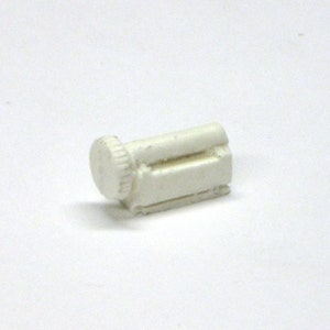 May include: White plastic model of a small engine with a round knob on the side.