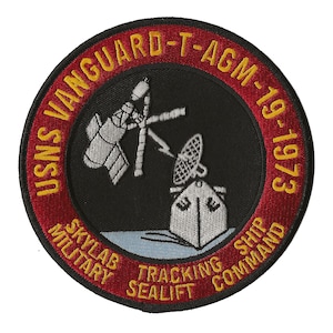 Op de afbeelding: Een geborduurde patch in rood, wit en blauw met de tekst "USNS Vanguard T-AGM-19 1973" in geel. De patch toont ook een satelliet en een schip met een radarantenne, en de tekst "Skylab Military Tracking Ship Sealift Command".