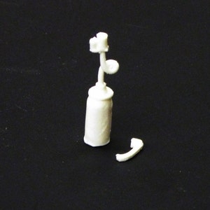 May include: White plastic model of a vintage telephone with a coiled cord. The phone is separated into two pieces, the base and the handset.