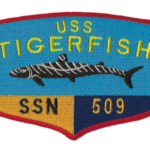 Puede incluir: Un parche bordado azul y amarillo con el texto "USS TIGERFISH SSN 509". Un pez tigre negro y blanco está representado en el centro del parche.
