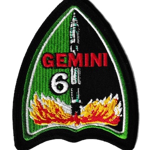 Op de afbeelding: Geborduurde patch met een zwarte rand, met een lancerende raket met vlammen, het woord "GEMINI" in rood en het nummer "6" in wit. De achtergrond is groen en zwart. De patch heeft een driehoekige vorm.