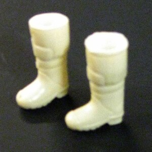 May include: A pair of off-white plastic boots with a fold-over top and a buckle detail.