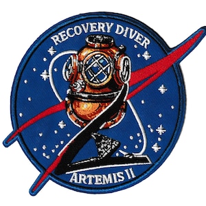May include: Circular embroidered patch with a vintage diving helmet in gold and brown on a blue background with white stars. The text "RECOVERY DIVER" and "ARTEMIS II" are displayed. A red and white swoosh design is also present.