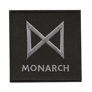 May include: A square, black embroidered patch featuring a gray, stylized, intersecting geometric design. The word "MONARCH" is embroidered in gray below the design. The patch is likely for clothing or accessories.
